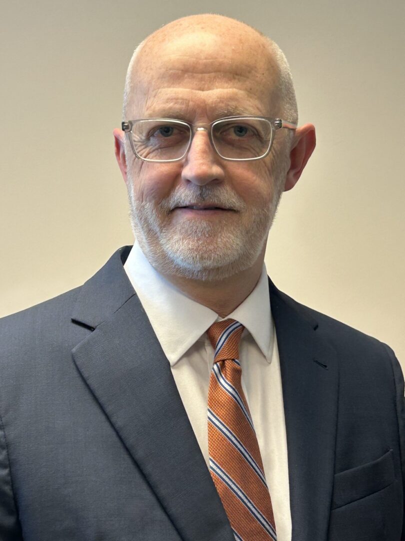 Professional elderly man with glasses in a suit and striped tie.